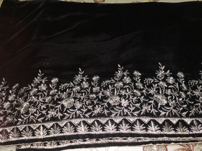 May include: Black velvet shawl with silver embroidery of floral designs. The embroidery is along the bottom edge of the shawl.