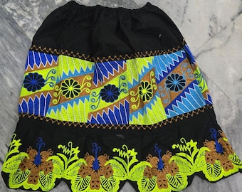 May include: Black skirt with vibrant embroidered details. The skirt has a black elasticated waistband and a colourful design with blue, green, and brown floral patterns. The hemline is scalloped with matching embroidery.