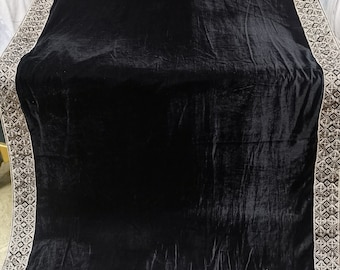 May include: A black velvet shawl with a silver embroidered border. The border features a repeating geometric pattern and a floral design at the bottom.