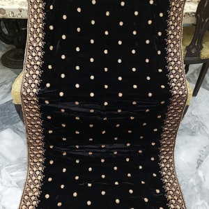 May include: A black velvet shawl with gold embroidery. The shawl features a floral pattern and is decorated with small gold dots.