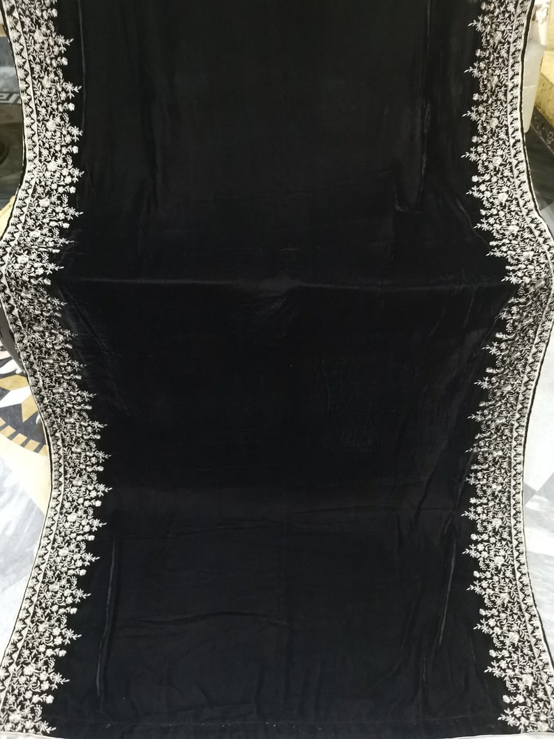 May include: A black velvet shawl with a white embroidered border. The embroidery features floral designs.