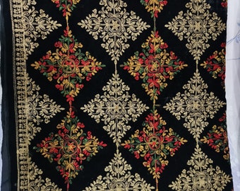 May include: Black velvet fabric with intricate gold embroidery featuring a repeating floral pattern. The embroidery includes red, green, and yellow accents.