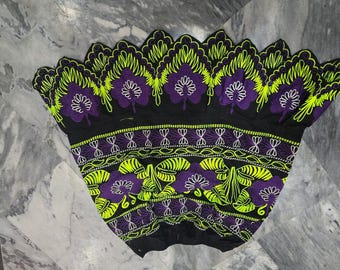 May include: Black fabric with detailed embroidery in purple, white, and neon green. The design features floral and leaf patterns, creating a decorative textile. The edges are scalloped, adding a unique touch to the overall design.