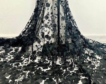 May include: Black floral lace fabric with a delicate, intricate design. The lace features 3D flowers and leaves, creating a luxurious and elegant look.