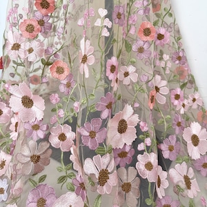 May include: Delicate sheer fabric adorned with embroidered flowers in pink, peach, and purple hues. The floral pattern showcases detailed stitching and brown centres, with green stems and leaves. Suitable for clothing or home decoration.