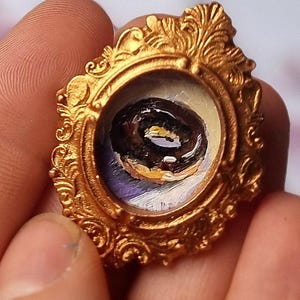 Miniatura de pintura al óleo: Dona realista con glaseado de chocolate en marco dorado ovalado con imán (1,5 x 2 cm). Mini arte gastronómico.