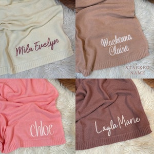 Pu&ograve; includere: Un collage di quattro coperte lavorate a maglia in crema, marrone chiaro, rosa e malva. Ogni coperta presenta nomi ricamati: Mila Evelyn in rosso scuro, Mackenna Claire in bianco, chloe in bianco e Layla Marie in bianco. Il testo STACKED NAME &egrave; visibile.