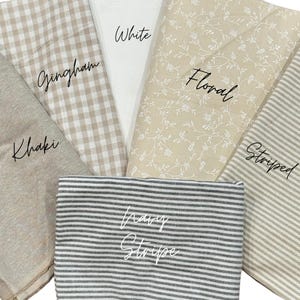 May include: A collection of fabric swatches featuring various patterns and colors. The set includes a solid khaki fabric, a beige and white gingham check, a solid white fabric, a beige floral print, a beige striped fabric, and a navy blue striped fabric.