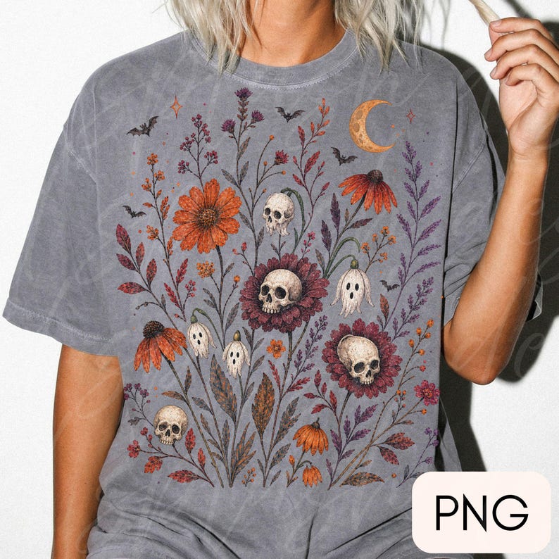 K&ouml;nnte beinhalten: Ein anthrazitfarbenes Kurzarm-T-Shirt mit einem Grafikdruck aus orangefarbenen und violetten Wildblumen, menschlichen Sch&auml;deln, kleinen Geisterfiguren und Flederm&auml;usen. Oben rechts befindet sich eine Mondsichel im botanischen Design.