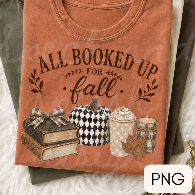May include: A rust-colored t-shirt featuring the text ALL BOOKED UP FOR fall in dark brown lettering. The graphic includes a stack of two books with a plaid bow, a black and white checkered pumpkin, a polka-dot mug with foam, and a candle.