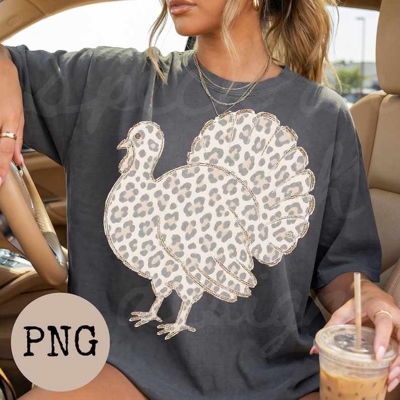 May include: A charcoal gray short-sleeve t-shirt featuring a large graphic of a turkey with a beige and brown leopard print pattern. The turkey is depicted in profile, showcasing its fanned-out tail feathers and detailed plumage with a spotted design.