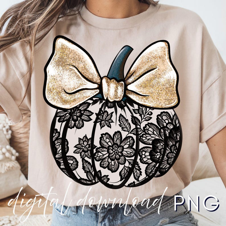 May include: A beige t-shirt featuring a decorative pumpkin design. The pumpkin has a black lace pattern, a gold glitter bow, and a dark blue stem. The words "digital download PNG" are written at the bottom of the image.