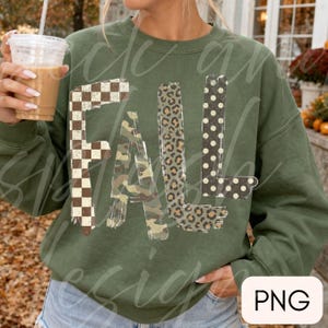 May include: An olive green crewneck sweatshirt featuring the word FALL printed in large letters. Each letter has a distinct pattern: the F is a brown and white checkerboard, the A is camouflage, the L is leopard print, and the L is black with white polka dots.