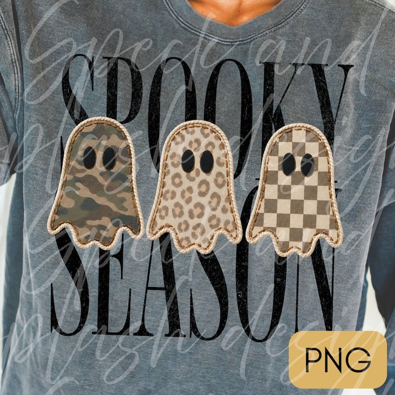 May include: A charcoal gray sweatshirt featuring the black text SPOOKY SEASON. Three ghost-shaped graphics are centered, each with a distinct pattern: one with camouflage, one with a leopard print, and one with a brown and white checkerboard pattern.