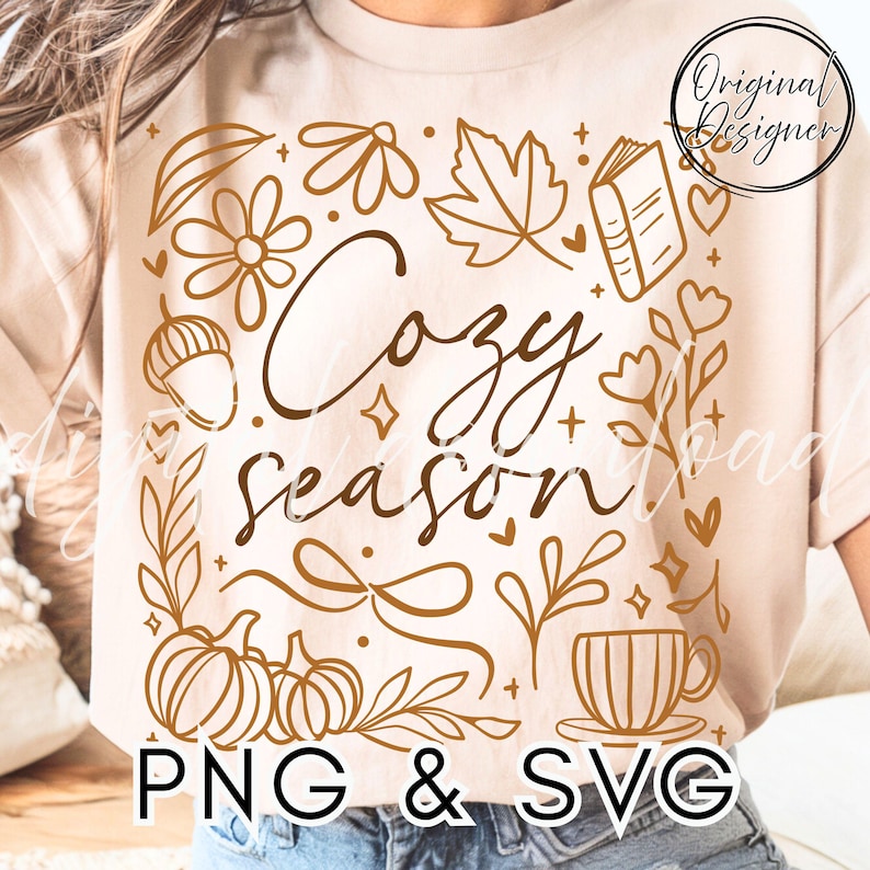 Pu&ograve; includere: T-shirt beige con un design grafico marrone con la scritta "Cozy Season" circondata da illustrazioni a tema autunnale come zucche, foglie e una tazza da t&egrave;. Il testo "PNG & SVG" &egrave; in basso.