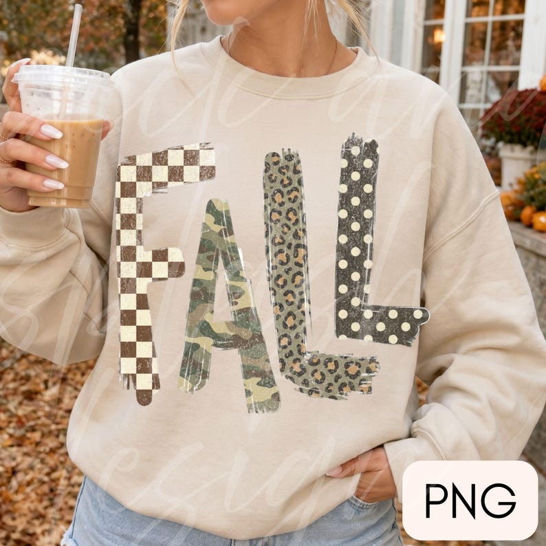 May include: A beige crewneck sweatshirt featuring the word FALL printed in large letters. Each letter has a distinct pattern: the F is brown and white checkered, the A is green camouflage, the L is leopard print, and the second L is black with white dots.