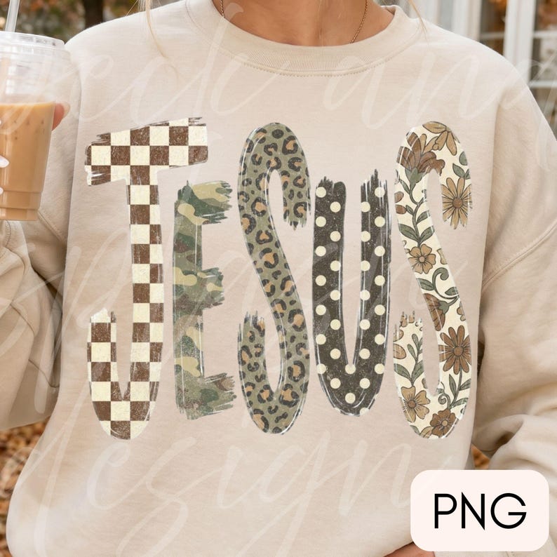 May include: A beige crewneck sweatshirt featuring the word JESUS in large, stylized letters. Each letter has a unique pattern: a brown and white checkerboard, green camouflage, leopard print, black with white polka dots, and floral print.
