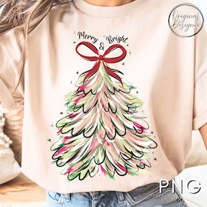 May include: A beige t-shirt features a Christmas tree design with the text "Merry & Bright." The tree is adorned with red, green, and pink brushstrokes, topped with a red bow. The design includes small star accents.