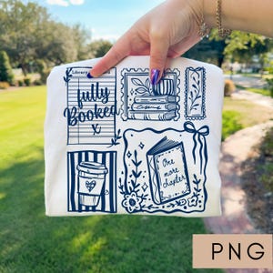 May include: Cream-colored t-shirt with a navy blue graphic design featuring a coffee cup, books, and the words "fully booked" and "one more chapter." The design includes a library card and postage stamp illustrations.