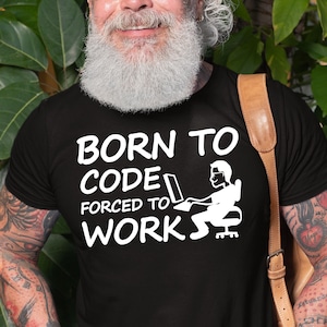 May include: A black t-shirt with white text that reads "Born to Code Forced to Work". The text is accompanied by a cartoon image of a person sitting at a computer.
