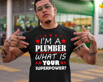 Pode incluir: Uma camiseta preta com texto branco que diz "Eu sou um encanador, qual é o seu superpoder?" com estrelas vermelhas ao redor do texto.