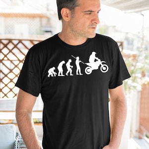 May include: A black t-shirt with a white graphic of the evolution of man, ending with a person riding a dirt bike.