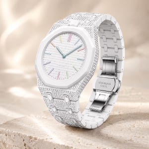 Puede incluir: Un reloj de pulsera blanco con bisel octogonal y brazalete de eslabones, ambos incrustados con cristales transparentes. La esfera blanca tiene un patrón texturizado y marcadores de hora multicolores. El cierre metálico dice STAINLESS STEEL.