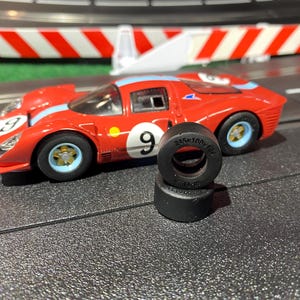 May include: Two black rubber tires for a slot car, with the text "215K 160Y 122" printed on the side.