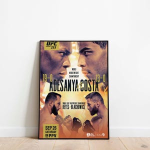May include: A framed UFC 253 poster featuring Adesanya vs. Costa and Reyes vs. Blachowicz. The poster has a black frame and displays the fighters' faces, records, and the event date, September 26, on PPV.