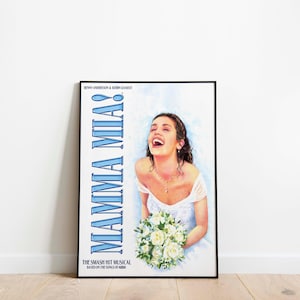 Puede incluir: Un póster enmarcado de la obra musical "Mamma Mia!" muestra a una mujer con un vestido blanco sosteniendo un ramo de flores blancas, riendo. El título "MAMMA MIA!" está en azul, con el texto "THE SMASH HIT MUSICAL BASED ON THE SONGS OF ABBA".