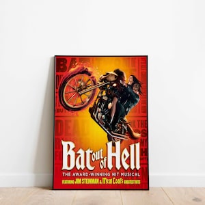 May include: Framed poster for the musical "Bat Out of Hell." The image shows a motorcycle with a flaming wheel, carrying two people. The poster has a red and yellow background with the musical's title and credits.