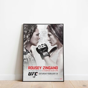 Puede incluir: Un póster de la UFC enmarcado con una imagen en blanco y negro de dos luchadoras enfrentadas. El póster incluye el texto "ROUSEY vs ZINGANO" en rojo, el logotipo de la UFC y los detalles del evento.