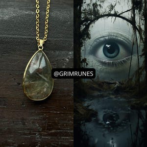 Puede incluir: Un collar dorado con un colgante en forma de lágrima. El colgante es una piedra transparente con inclusiones verdes y marrones. La imagen también presenta un ojo surrealista en un entorno pantanoso, con el texto "@grimrunes".