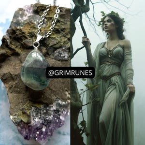 May include: A silver necklace with a teardrop-shaped green fluorite pendant. The pendant has a light green color with darker green veins. The necklace is on a rock background with purple crystals.