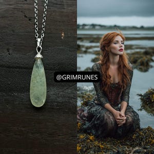 May include: A teardrop-shaped pale green gemstone pendant hangs from a silver-toned metal chain. The pendant features subtle dark inclusions within the stone. The text @GRIMRUNES is displayed in a black rectangular box next to the jewelry piece.