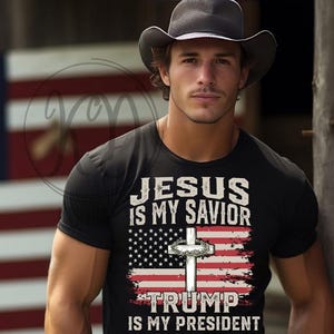 May include: A man wearing a black t-shirt with the text "Jesus is my savior" and "Trump is my president" printed on it. The shirt features an American flag design with a cross in the center.