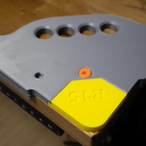 May include: A grey plastic corner brace with five holes and a yellow accent with the word "K2S" printed on it.