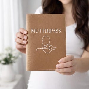 Könnte beinhalten: Ein hellbrauner Einband mit dem Wort "MUTTERPASS" in weißer Schrift. Darunter eine weiße Strichzeichnung eines Fötus. Der Einband wird von einer Person gehalten.