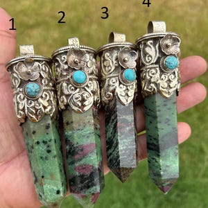 May include: Four gemstone pendants with silver-colored metal caps and turquoise accents. The gemstones are green with black and red inclusions. Each pendant is a different shade of green and has a unique pattern.