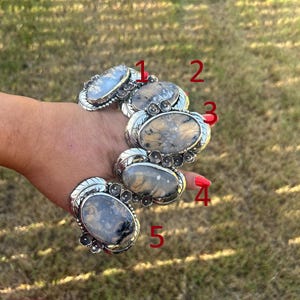 May include: A silver link bracelet featuring five large oval-shaped dendritic agate stones with unique dark fern-like inclusions. Each stone is set in a decorative silver frame with small floral accents. The numbers 1 through 5 are marked in red.