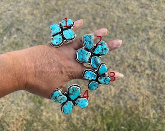 May include: Four silver rings featuring clusters of bright blue turquoise stones with dark matrix patterns. Each ring is numbered in red, with ring 1 at the top, rings 2 and 3 in the middle, and ring 4 at the bottom, showcasing natural stone variations.