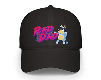 May include: Black baseball cap with the text "RAD DAD" in pink and blue, and a cartoon dog character. The cap has a curved peak and a structured crown, suitable for casual wear.