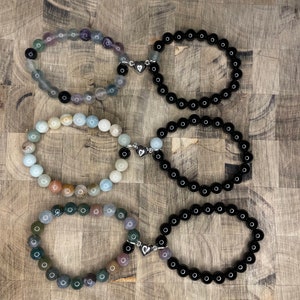 Peut inclure: Six bracelets avec des breloques en forme de c&oelig;ur argent&eacute;s. Trois bracelets sont noirs et trois sont faits de pierres de diff&eacute;rentes couleurs.