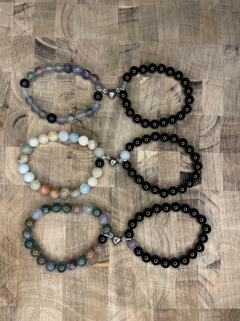 Peut inclure: Six bracelets avec des breloques en forme de c&oelig;ur argent&eacute;s. Trois bracelets sont noirs et trois sont faits de pierres de diff&eacute;rentes couleurs.