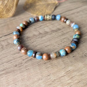 Peut inclure: Un bracelet de perles composé d'un mélange de perles en bois, bleues et à motifs. Le bracelet présente une variété de couleurs, notamment le marron, le bleu et l'or. Le bracelet est conçu comme un accessoire de mode.