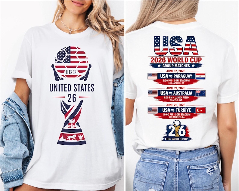 May include: White t-shirt featuring a soccer ball design with the American flag pattern and the text "UNITED STATES 26". The back of the shirt lists the USA 2026 World Cup group matches, including dates, times, and locations.