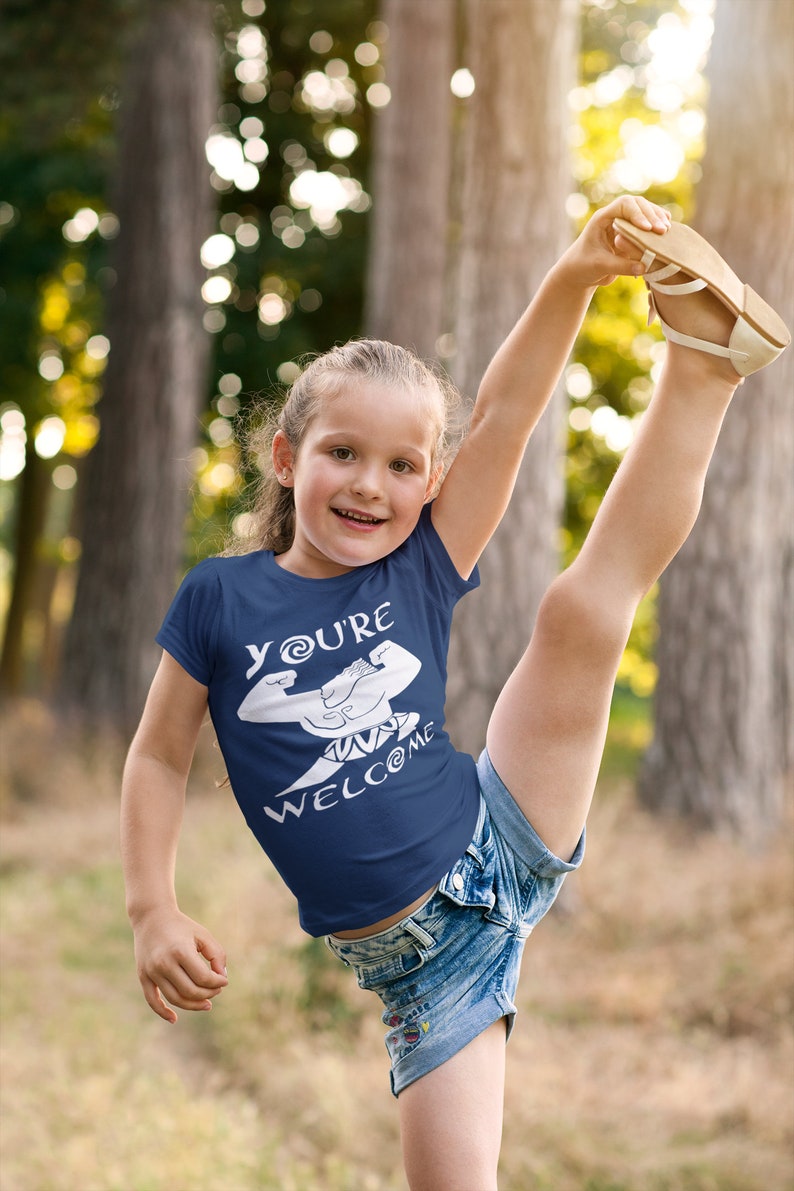 May include: A young person wearing a navy blue t-shirt with a white graphic of a cartoon character with the text "You're Welcome". The person is wearing denim shorts and has their leg raised in the air.