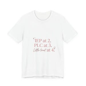 Puede incluir: Camiseta blanca con el texto "IEP at 2. PLC at 3. Little treat at 4." en rosa suave. La camiseta tiene cuello redondo y mangas cortas. El texto está centrado en la parte delantera.