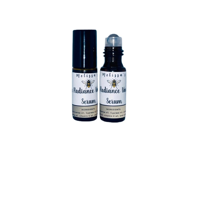 K&ouml;nnte beinhalten: Zwei bernsteinfarbene Glas-Rollflaschen mit schwarzen Kappen und wei&szlig;en Etiketten. Die Etiketten zeigen eine Bienenillustration und den Text "Melissa's Radiance Serum".