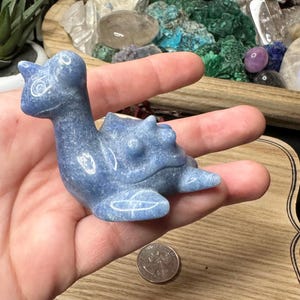 May include: A blue, carved, gemstone turtle figurine. The turtle is sitting on its hind legs with its head turned to the side. The figurine is about the size of a quarter.